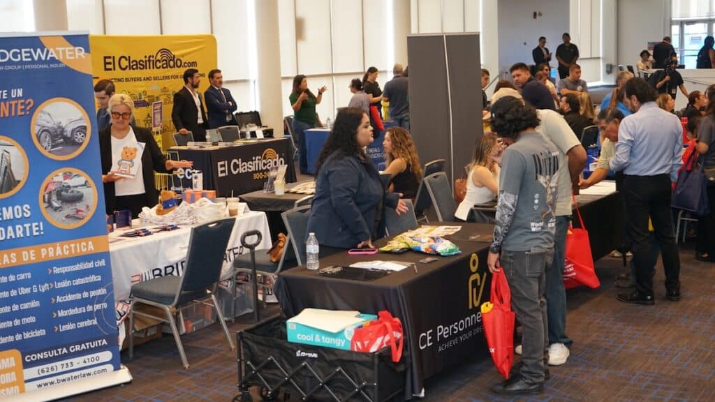 Attendees to the El Clasificado's job fair in Cerritos College talking with hiring teams