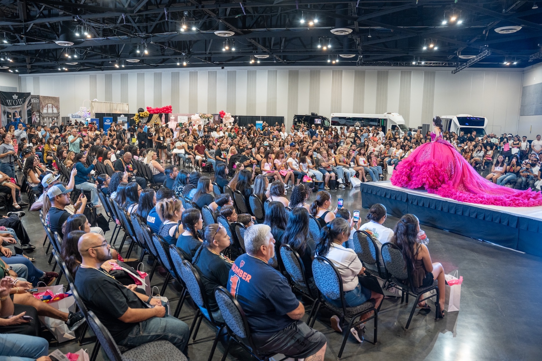 A model in a bright pink quinceañera gown walks the runway before a large crowd at the Quinceanera.com Expo & Fashion Show in Ontario, California.