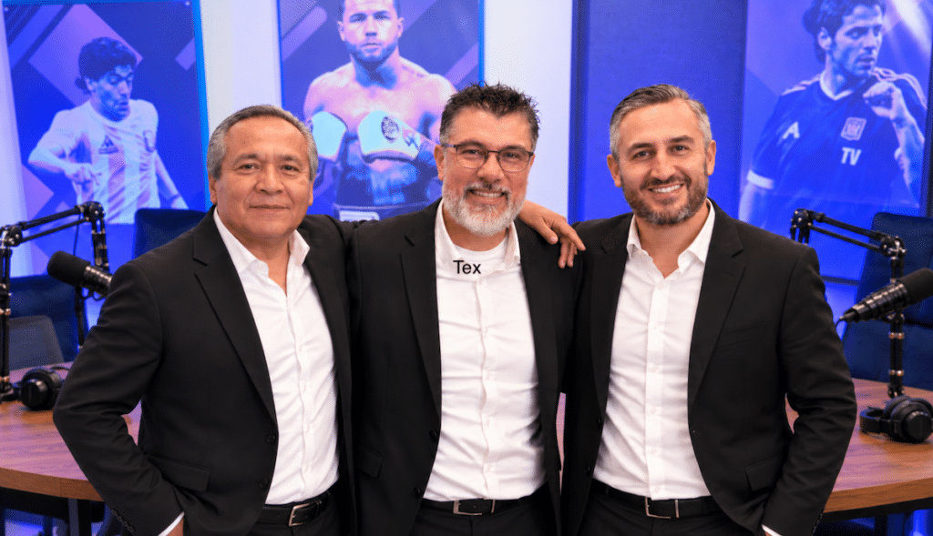 From left to right, soccer analyst José Francisco Sánchez, producer Giancarlo Bresani, and host Carlos Maciel pose together in the Golpe de Estadio studio, with sports portraits and microphones behind them.